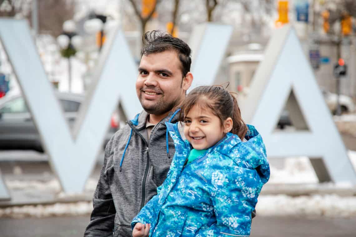Afghan man and little girl standing in front of the Ottawa sign