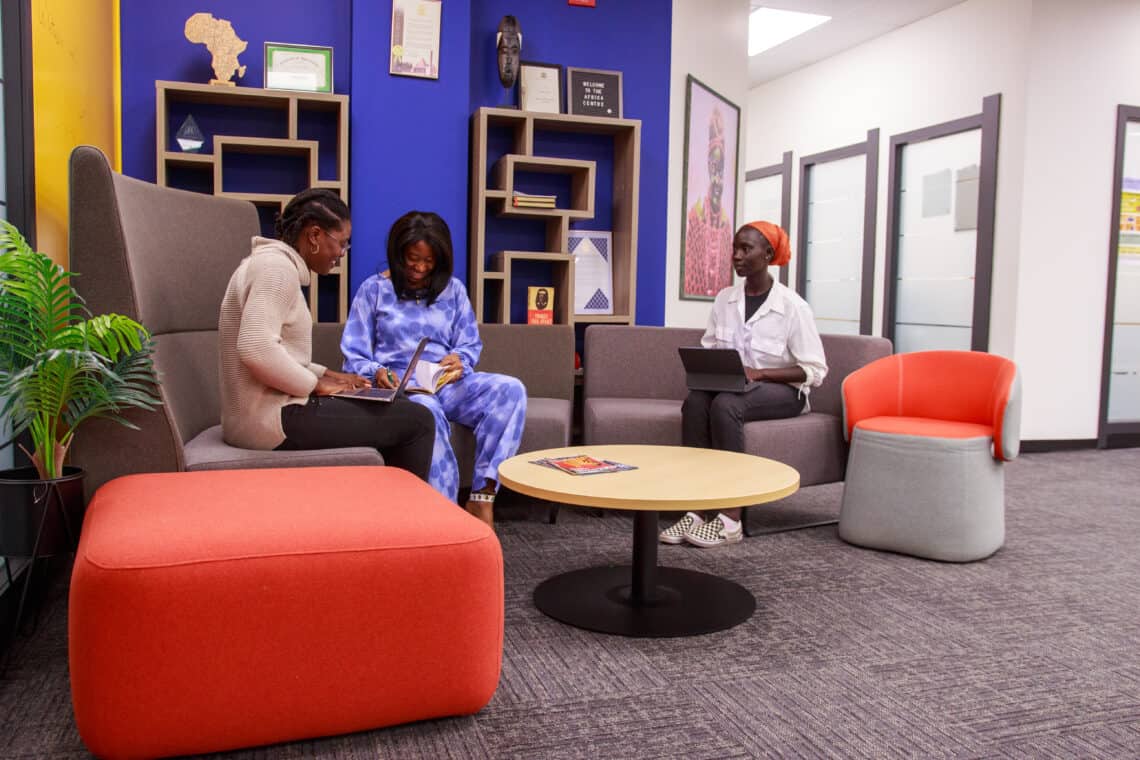 People seated at couches with laptops in an office space