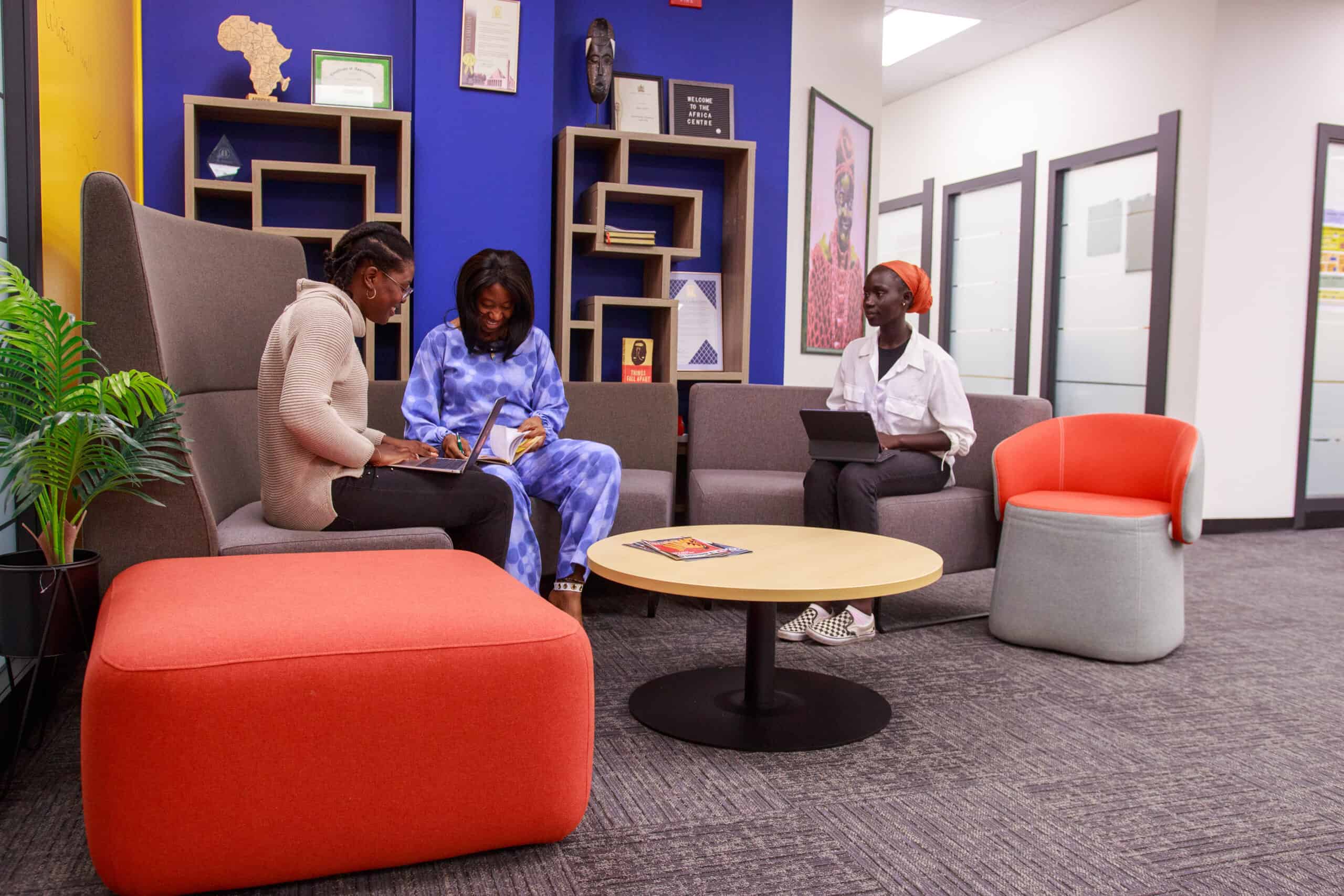 People seated at couches with laptops in an office space
