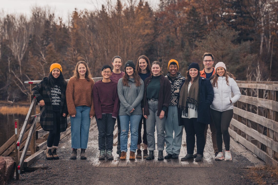 Ten people smiling while posing together on a bridge.