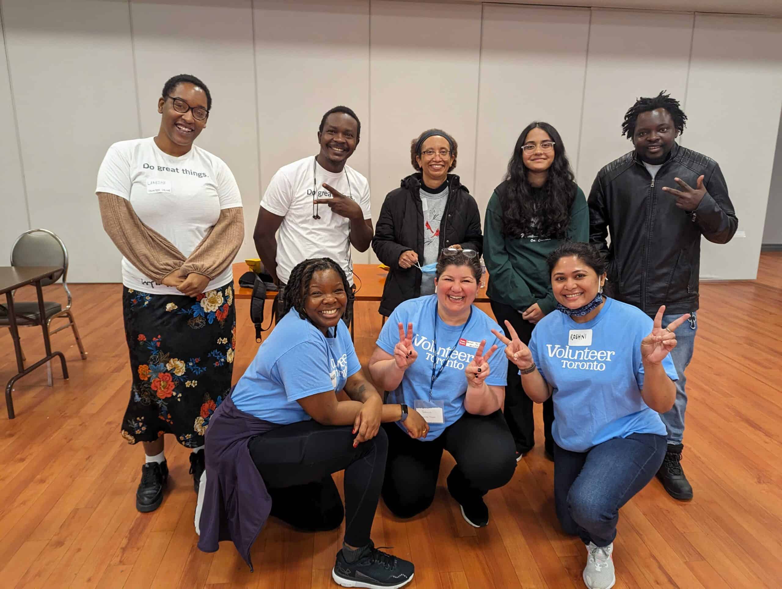A group of eight people posing for the camera. Three people are wearing "Volunteer Toronto" t-shirts
