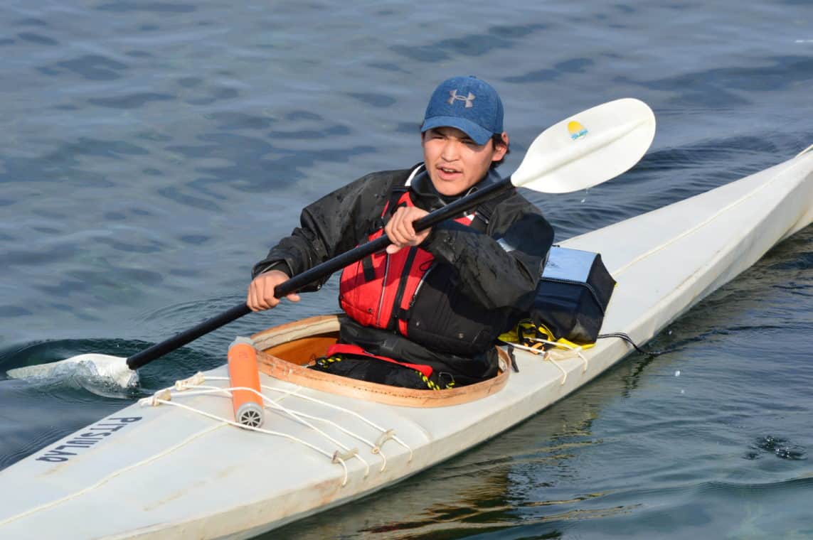Person paddling a qajaq in the water.