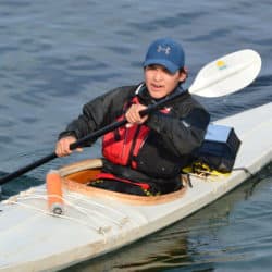 Person paddling a qajaq in the water.