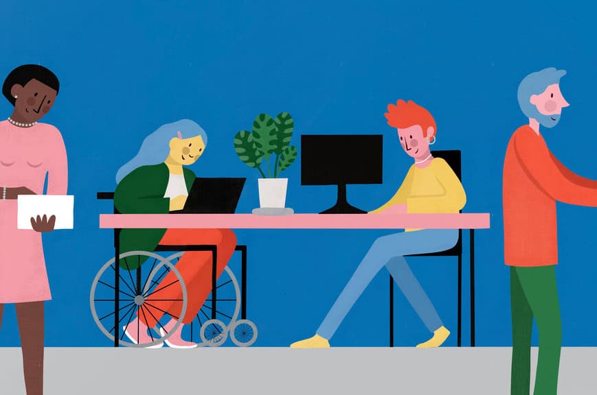 A busy office scene. Two people sit at a desk on their computers and laptop. One of them is in a wheelchair. Either side of them are two office workers who are busy working.