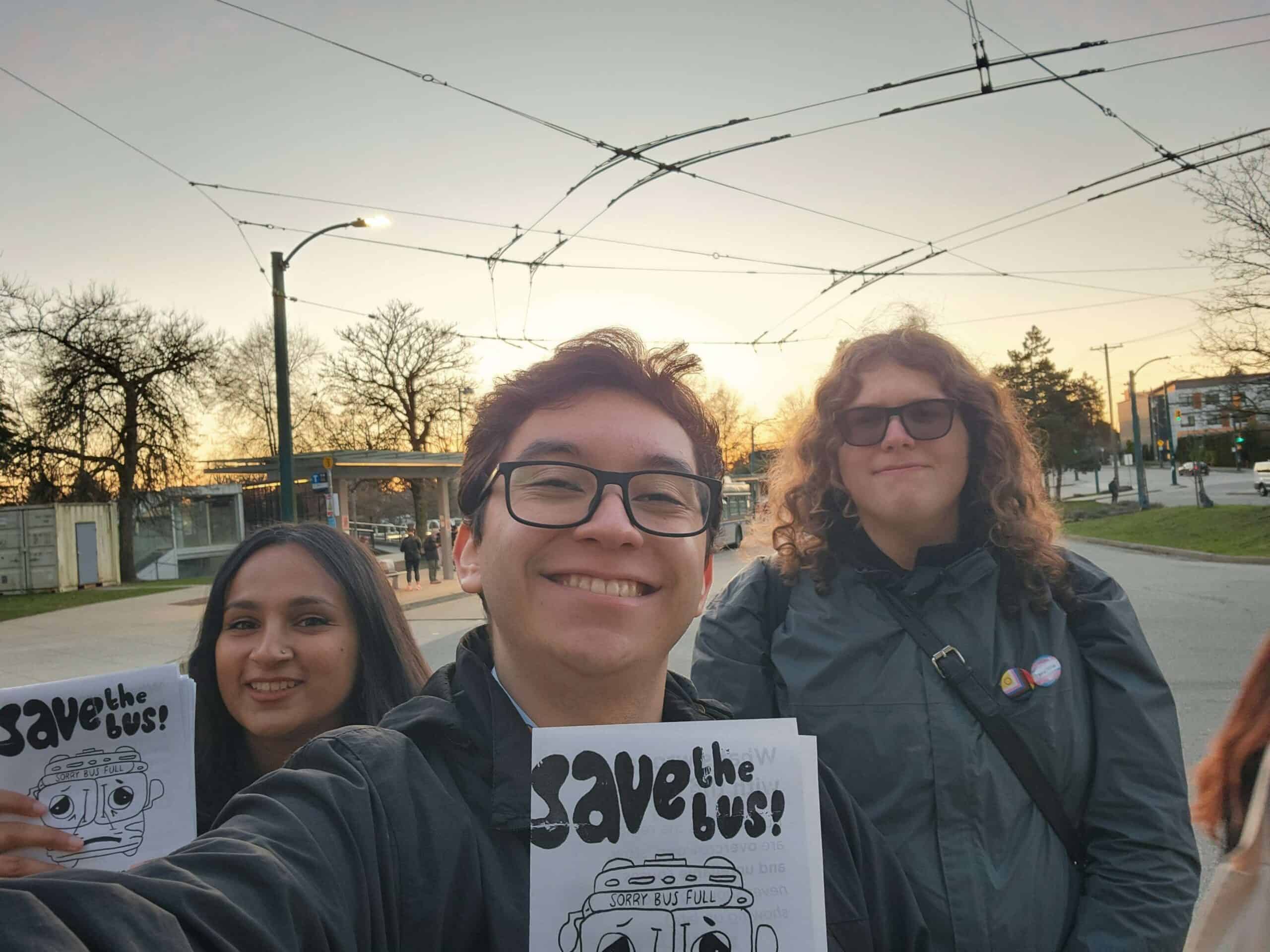 Three people smiling and holding pamphlets that say "save the bus!"
