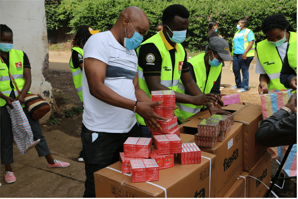 People in an assembly line outdoors moving boxes and packages.