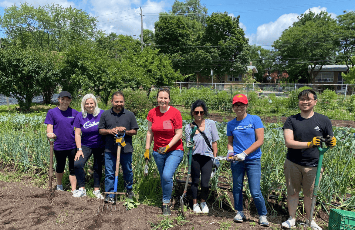 People posing with shovels in front of a garden